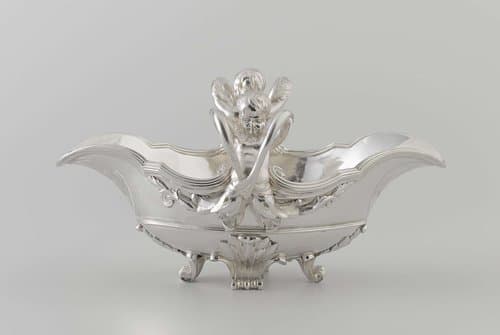 Sauskom met op de korte zijde kinderfiguren, waarvan de armen handvatten vormen