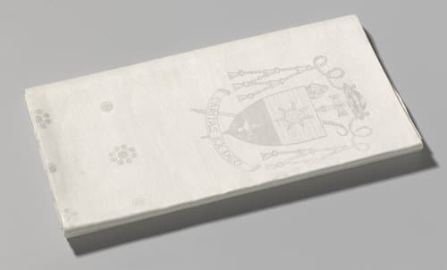Wit linnen damasten tafellaken met dessin "Braam" en "Haantjes" (cirkeltjes) en het bisschoppelijk wapen van mgr. Moors van Roermond
