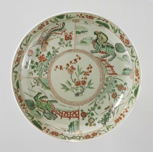 Saucer-dish with celadon glaze, prunus sprays, shishi, peacock and feng huangs by anonymous