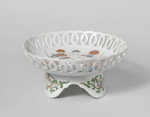 Saucer-dish on tripod with flowering plants near rocks by anonymous
