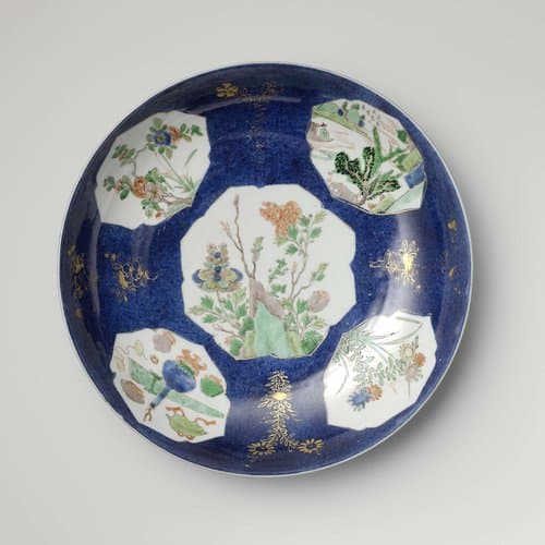 Schotel met bleu poudré en cartouches in reserve met bloemtakken, landschappen en kostbaarheden by anonymous