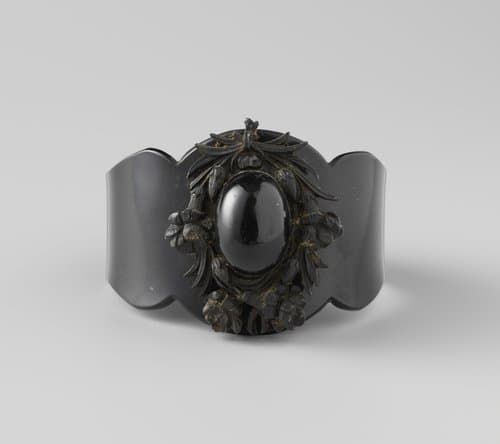 Armband van balein, breed van voren en enigszins gegolfd. Op bovenkant een krans van bloemen en bladeren met in het midden een ovaal. by Unknown Artist