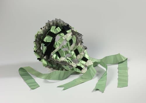 Bonnet-coiffure van groen satijn, zijden lint, bandfluweel en kant op een zwart tulen ondergrond genaaid by anonymous