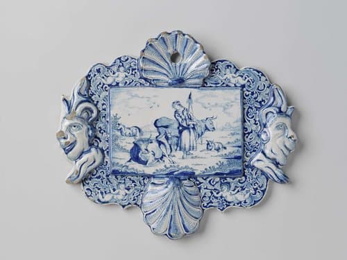 Plaat, rechthoekig, met twee schelpen en twee narrenkoppen in reliëf by De Bloempot
