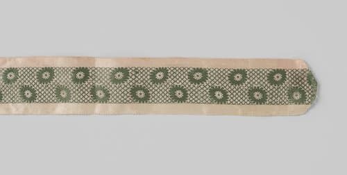 Lint of kousenband van zijde met lancé-effect; over de gehele lengte van het roze lint loopt een groene baan met een rasterpatroon waarin margrieten zijn verwerkt by anonymous