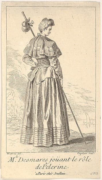 Actress Charlotte Desmares playing the role of a pilgrim, shown from behind with her head turned toward the right, she holds a walking stick, scallop shells adorn her cape